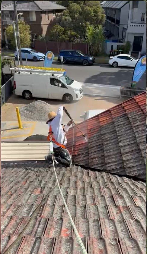 Before — VD Painting crew member harnessed up and pressure washing a weathered terracotta tile roof in NSW